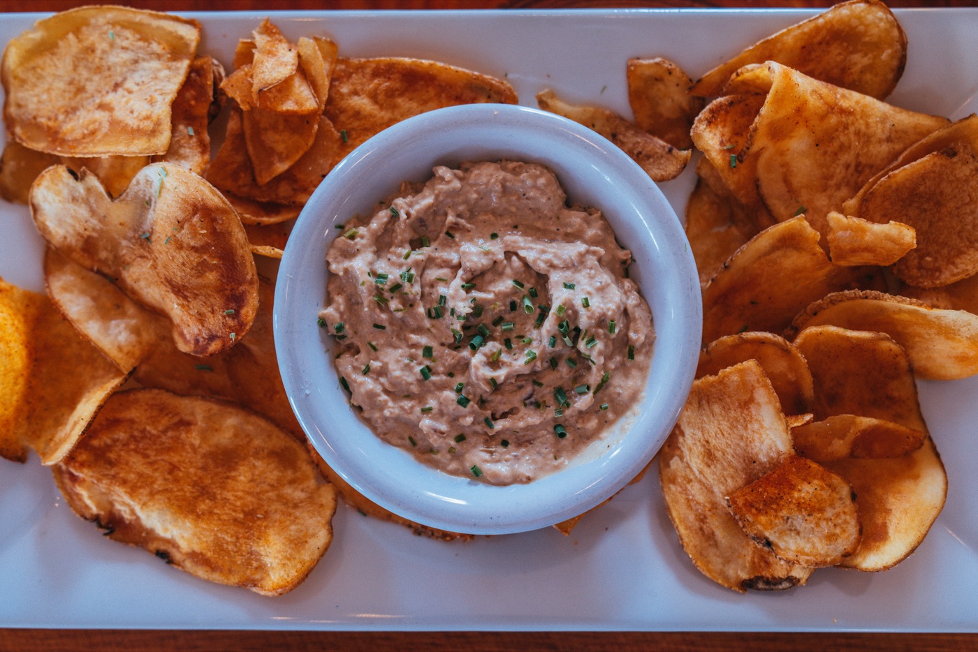 Hand-cut cajun potato chips fanned around a bowl of homemade onion dip