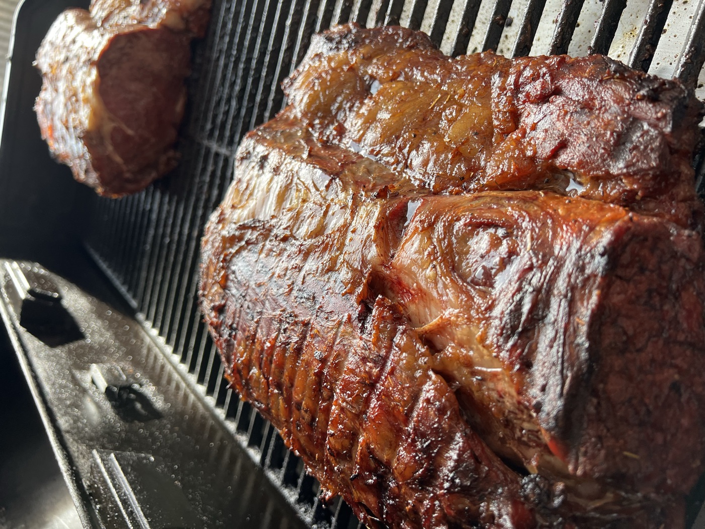 A finished smoked prime rib resting on a board beside the smoker