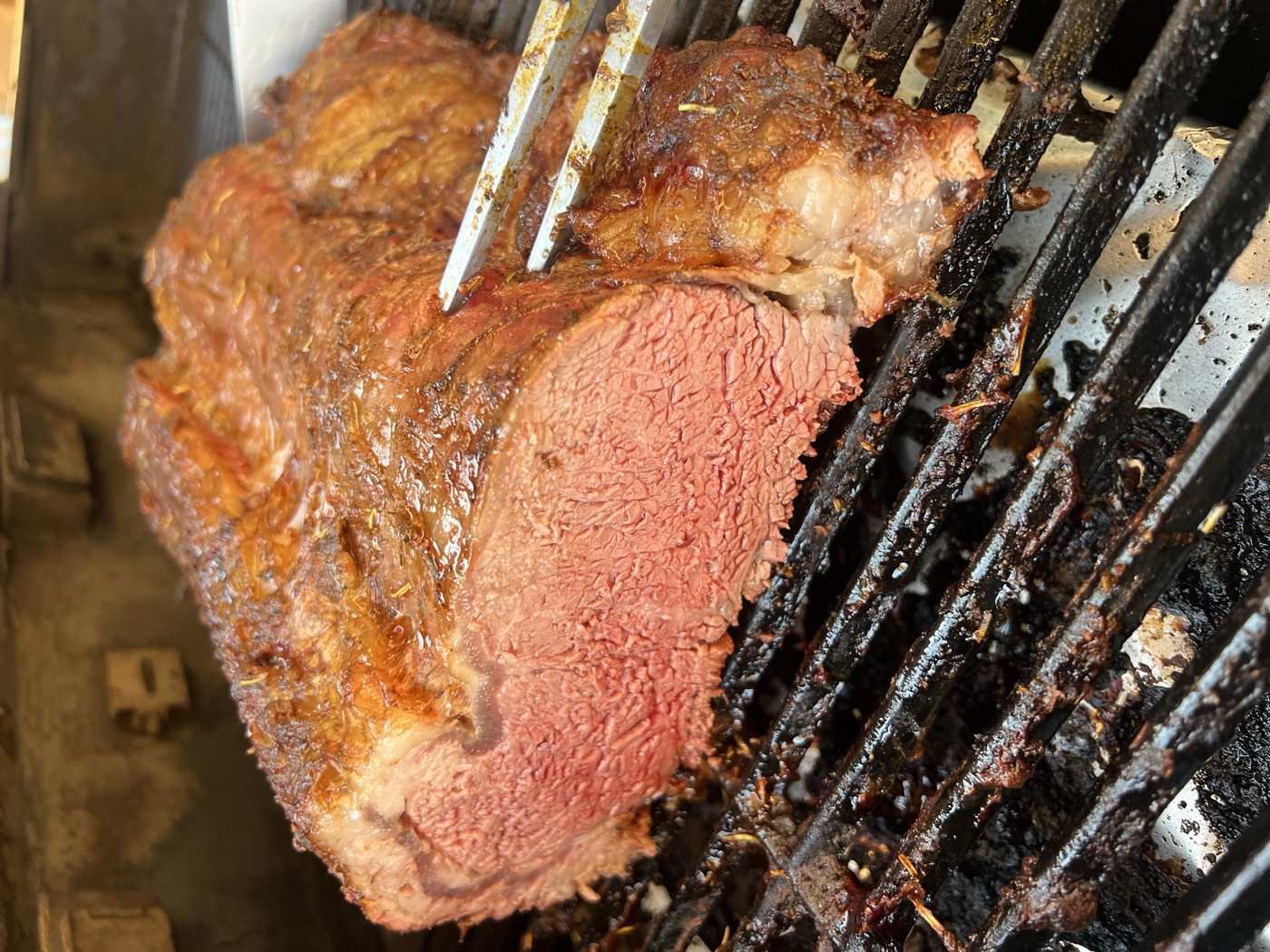 A carving knife opening a smoked prime rib to a rosy centre